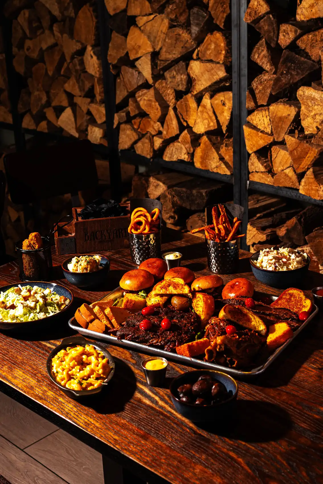 Full BBQ platter with brisket, sliders and sides on a hardwood table at Backyard Smokehouse Edmonton