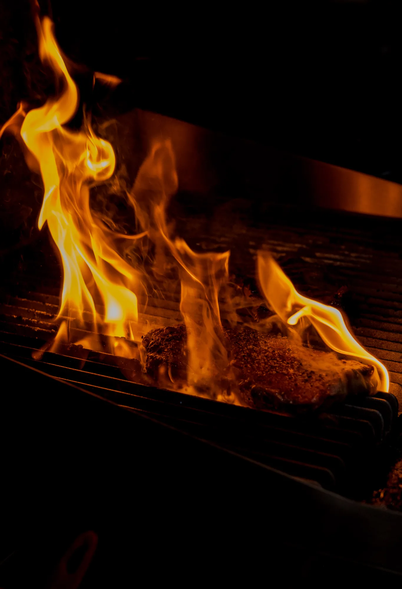 Open flame grill searing meat at Backyard Smokehouse Edmonton