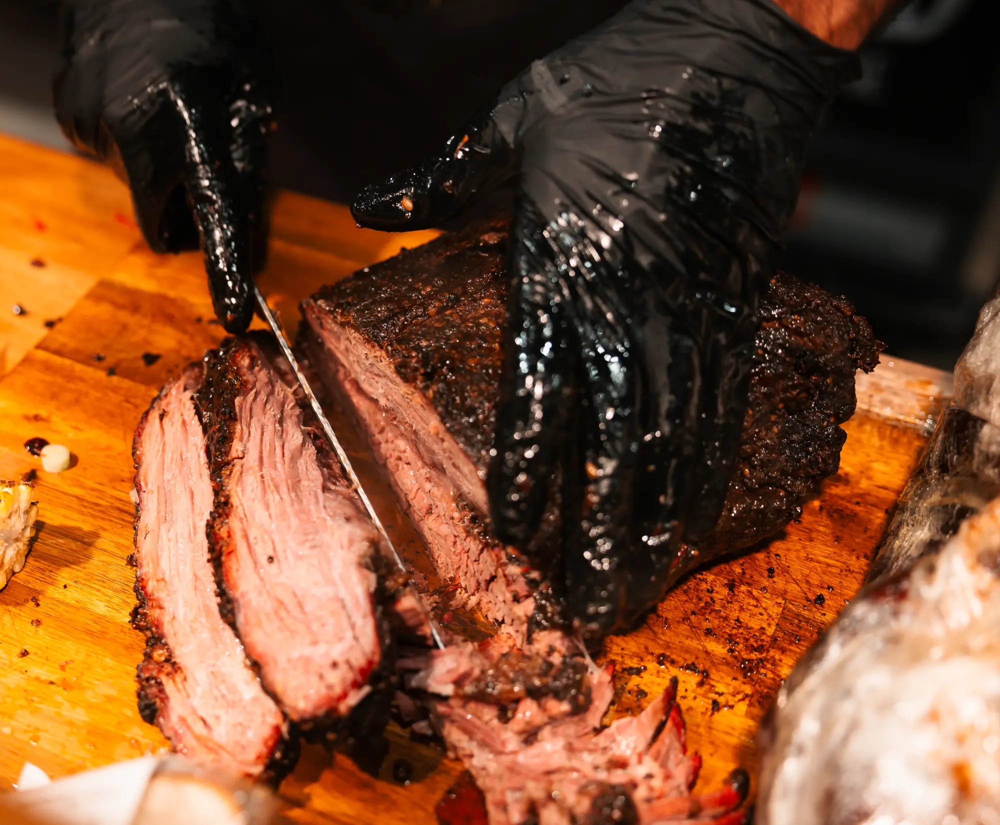 Chef slicing smoked brisket on a wooden board at Backyard Smokehouse Mississauga