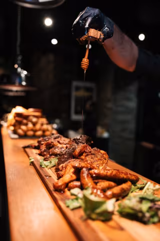 Chef drizzling sauce over a smoked platter at Backyard Smokehouse Mississauga