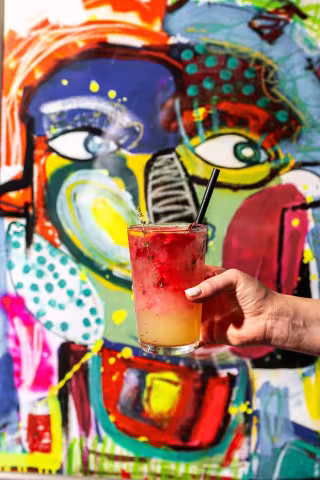 Signature cocktail in front of the graffiti art wall at Backyard Smokehouse Toronto