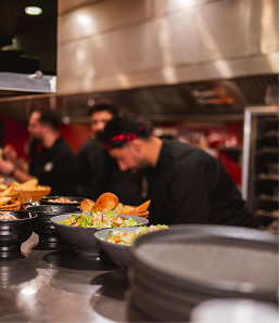 Professional chefs preparing fresh BBQ orders in the Backyard Smokehouse Edmonton kitchen.