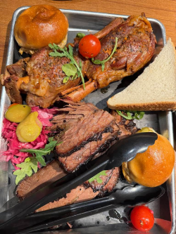 Backyard Smokehouse Edmonton BBQ platter with sliced brisket, sliders, and house-made pickles on a metal tray